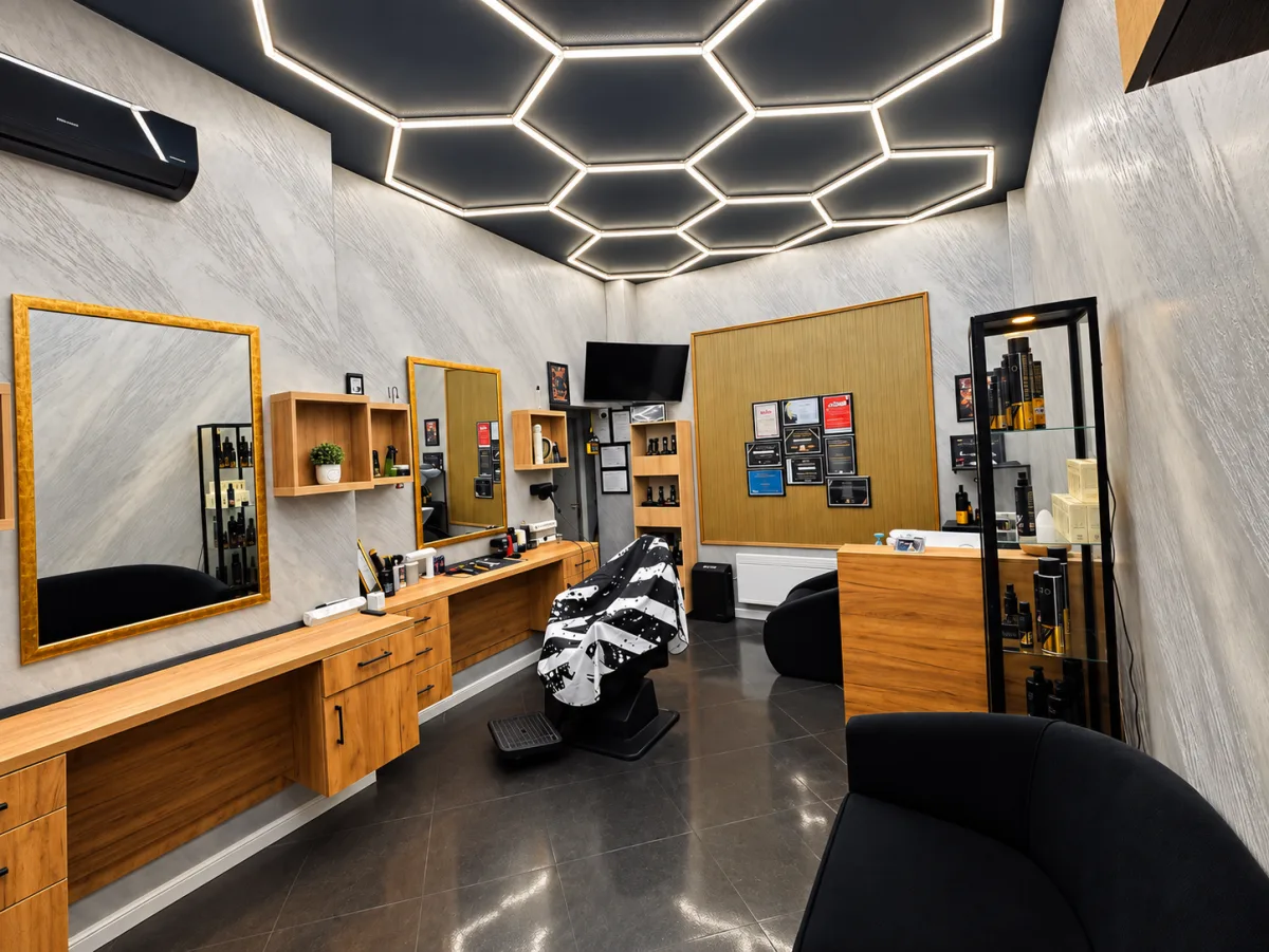 Interiorul salonului DenisTheBarber din Buzău, cu scaun de frizerie, oglinzi mari și tavan decorativ cu iluminat hexagonal